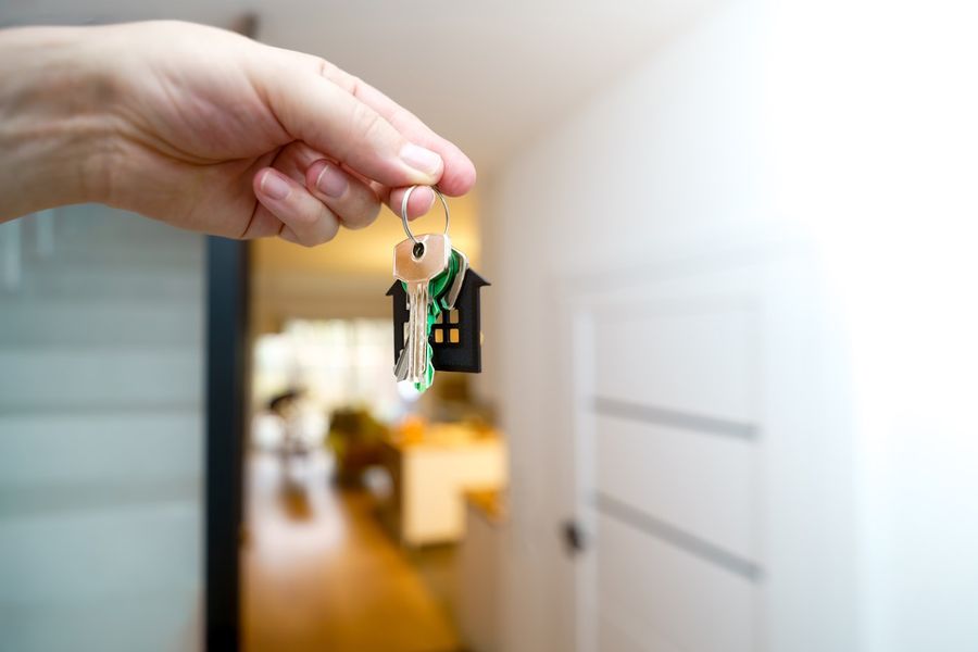 Mão segurando a chave de uma porta de casa
